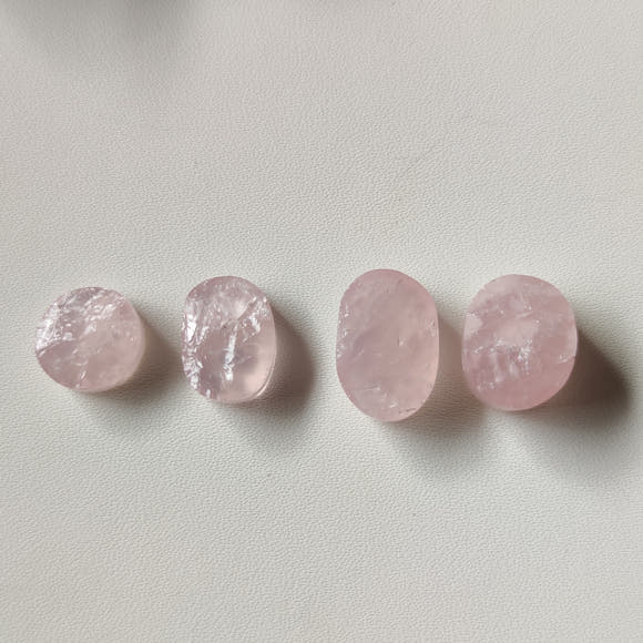Cuarzo rosa cabujón natural nr.3 (15×10 mm) con vetas e inclusiones visibles, fondo oscuro
