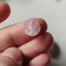 Cabujón de cuarzo rosa en bruto ø10 mm junto a moneda para referencia de escala