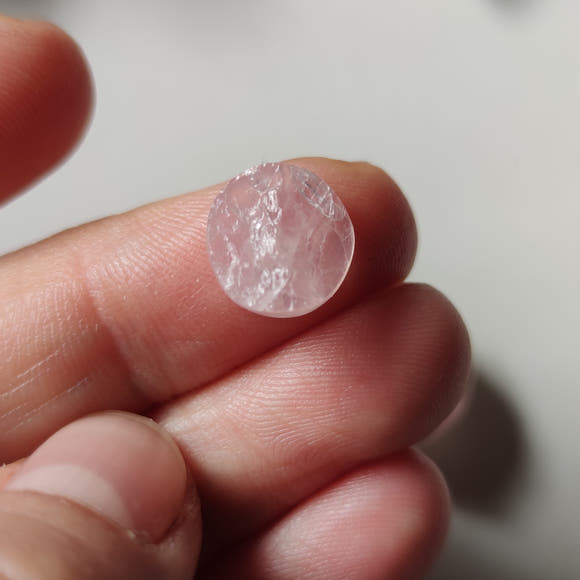 Cabujón de cuarzo rosa en bruto ø10 mm junto a moneda para referencia de escala
