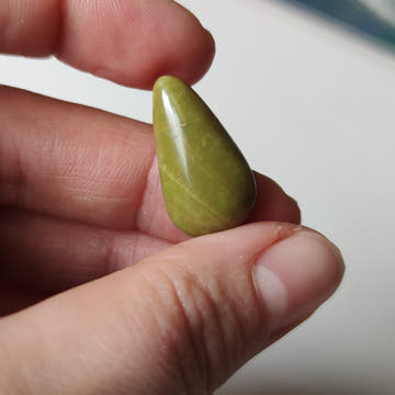 Cabujón lágrima de ópalo verde natural de 25×13 mm, pulido espejo, sobre fondo oscuro