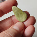 Cabujón ópalo verde lágrima con matices translúcidos bajo luz directa, fondo neutro